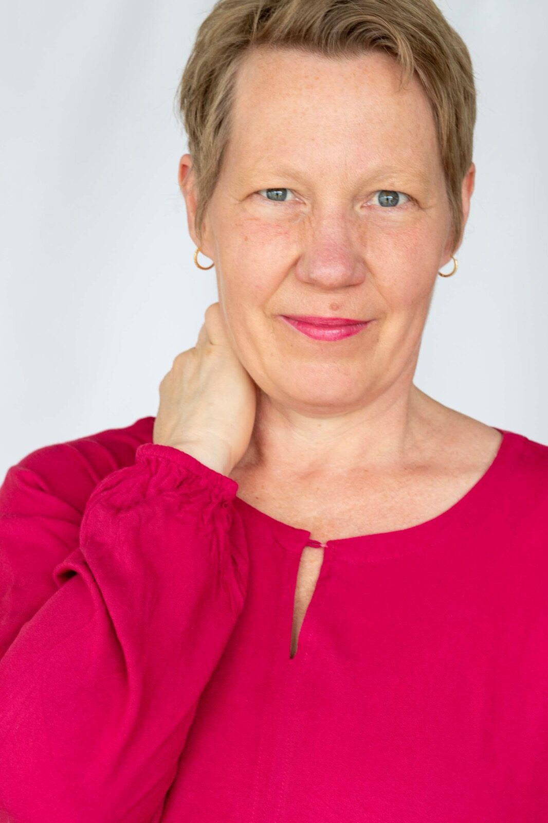 Marion Hanekamp lächelt in die Kamera vor hellem Hintergrund